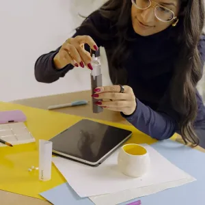 Kvinne som holder Paperlike Cleaning Kit v2 ved siden av et nettbrett under skånsom skjermrengjøring