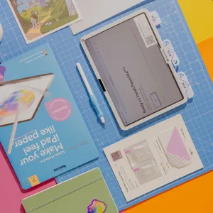 Paperlike 3 skärmskydd för iPad, förpackning och installationssats med mall, kort och pekpenna på en skärmatta