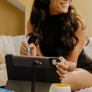 Kvinna som använder en iPad med en matt Paperlike-yta i ett foliofodral och håller en Apple Pencil