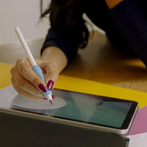 Blått ergonomiskt penngrepp på Apple Pencil, greppat av en hand som ritar på surfplatta; närbild med spets och skärm klart.