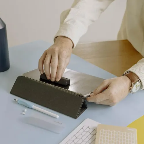 Paperlike Cleaning Kit v2 used to clean a tablet screen, with cleaning accessories on a tabletop
