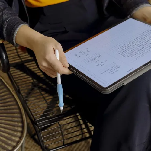 Ergonomiskt blått silikongrepp på Apple Pencil, konturerat med fingerstöd och placerat nära spetsen, hålls över surfplatta.