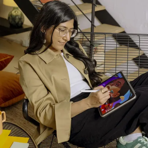 Kvinna som använder en pekpenna på en iPad med skärmskyddet Paperlike och ritar med papperslik känsla inomhus